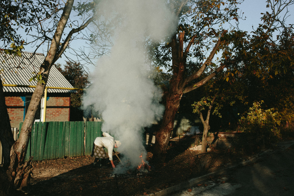 An elderly woman burns autumn leaves in the village of Semonovka, October 2014